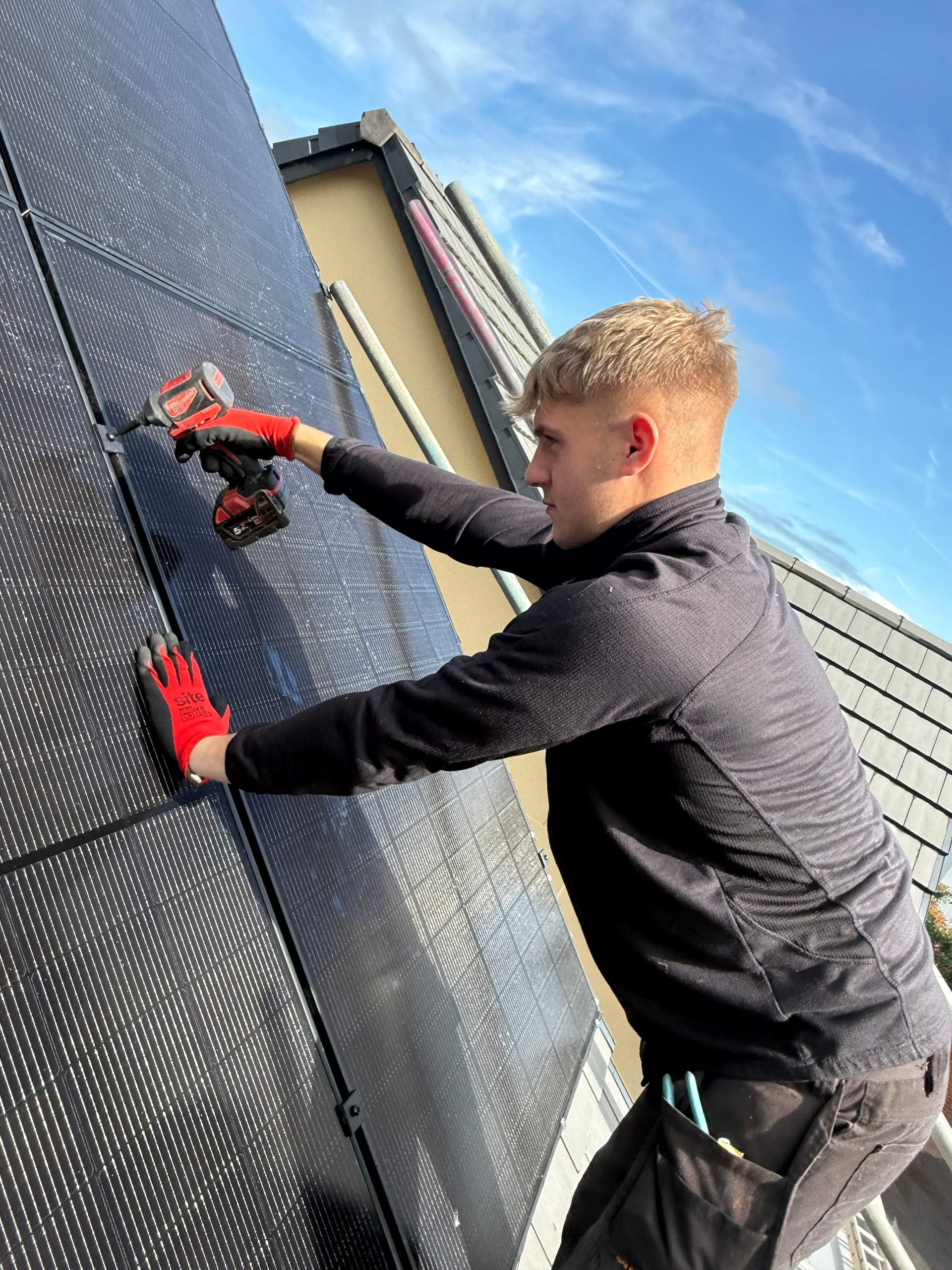 Djuka engineer fixing solar panels in place on a Midlands rooftop