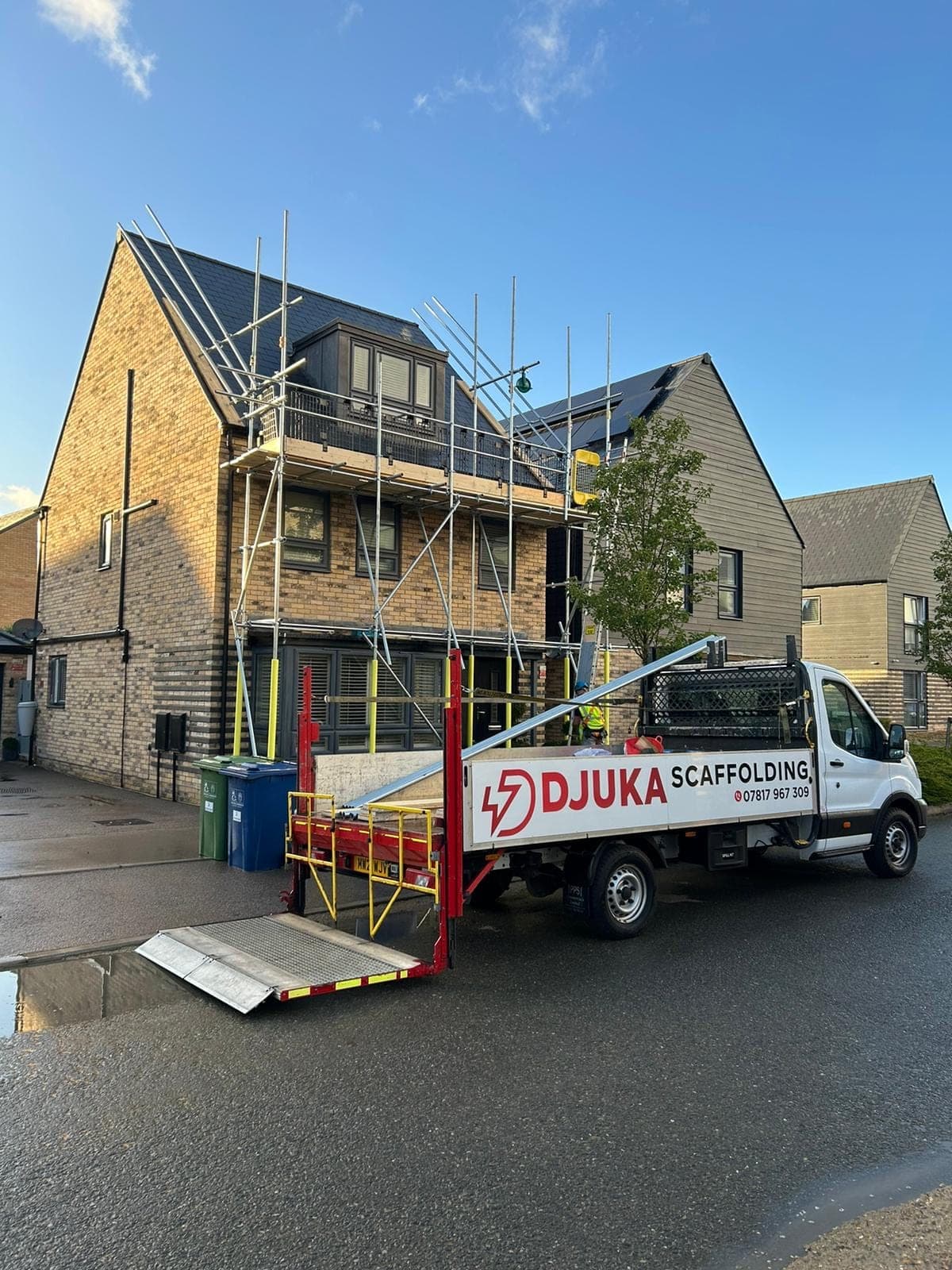 The branded Djuka Scaffolding truck on-site at a modern Midlands home, scaffolding erected, panels going on the roof